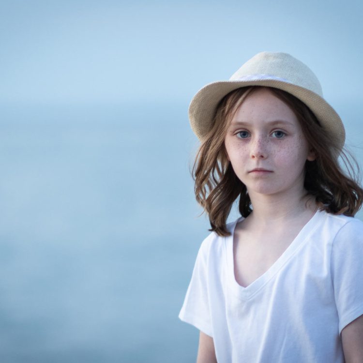 Young girl with freckles and a straw hat on the beach in Boca Raton