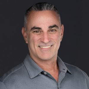 Headshot of a man with gray hair, wearing a gray flannel button down shirt.
